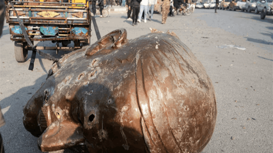 Syrians in Damascus trample on toppled statue of Assad's father